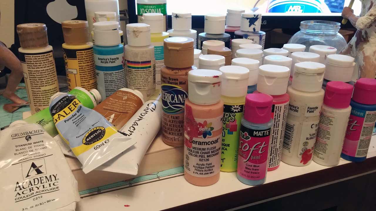 assorted acrylic and fabric paints on desk