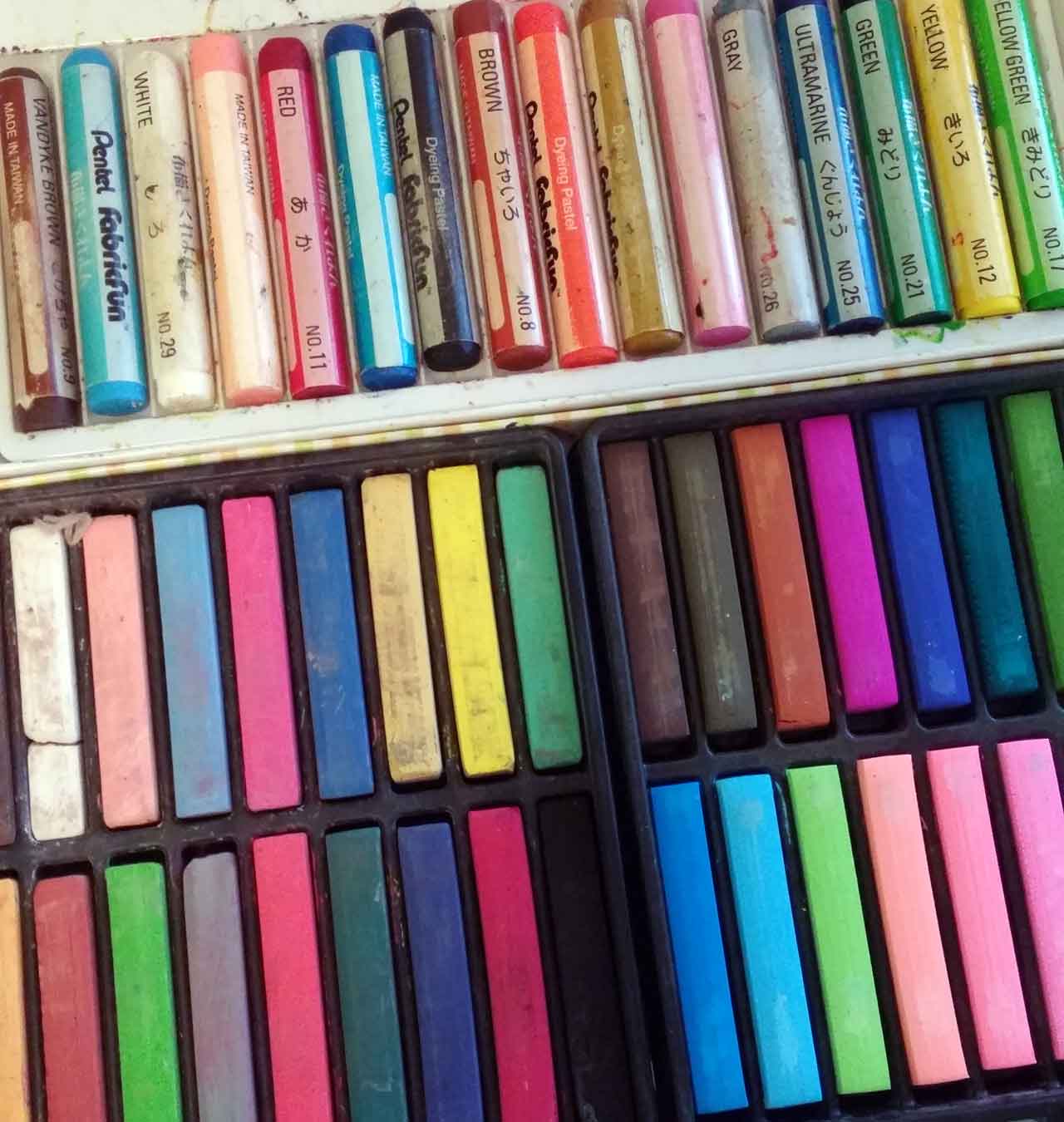 assorted fabric and colored pastels on desk